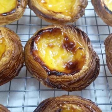 pasteis de nata cooling down on a rack