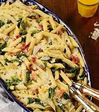 Kale Pasta Salad in a dish with serving utensils