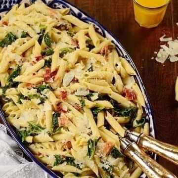 Kale Pasta Salad in a dish with serving utensils