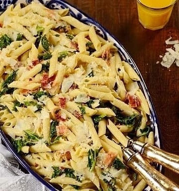 Kale Pasta Salad in a dish with serving utensils