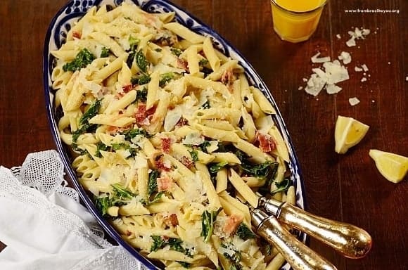 Kale Pasta Salad in a dish with serving utensils