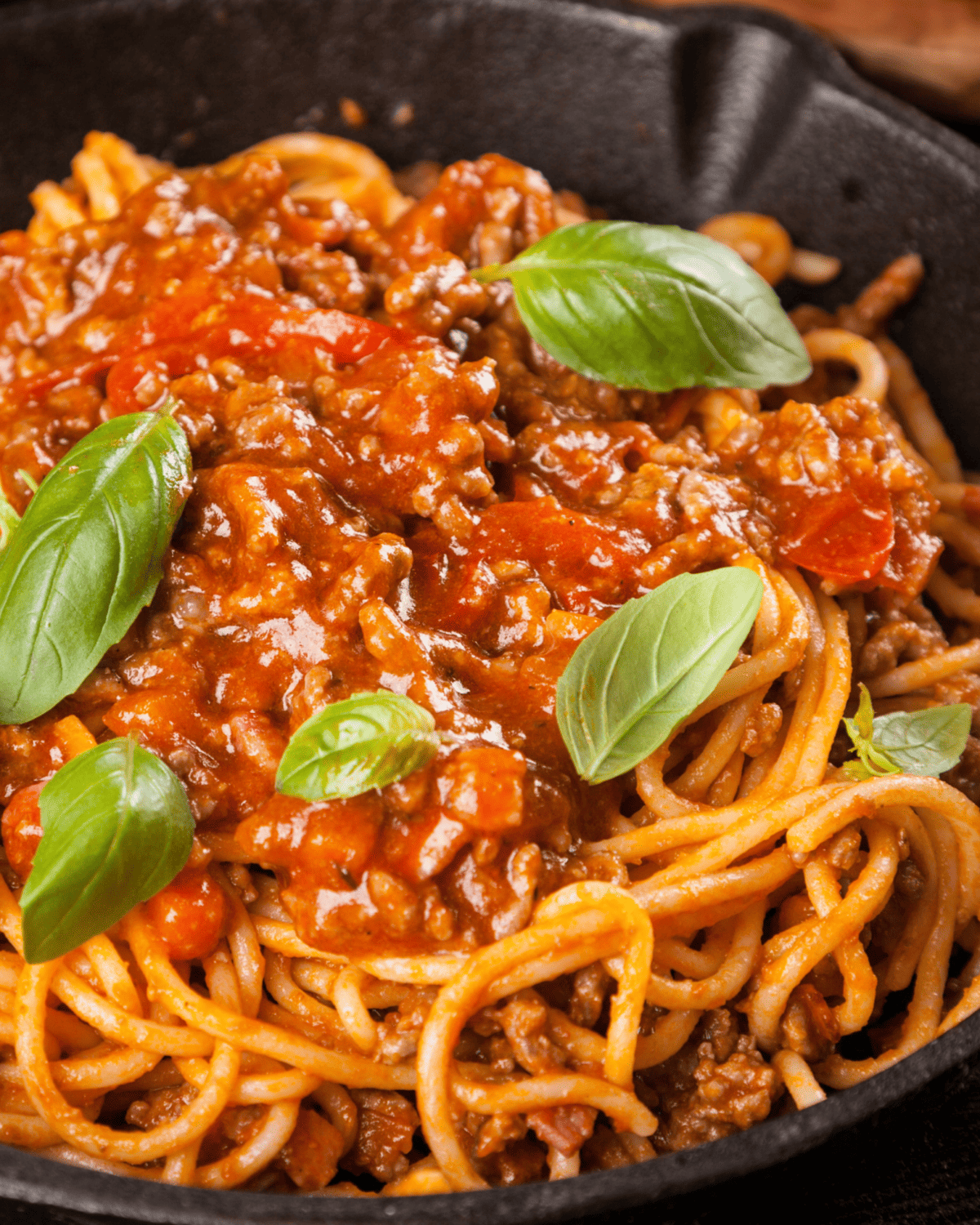 spaghetti and meat sauce plus basil ina closeup.