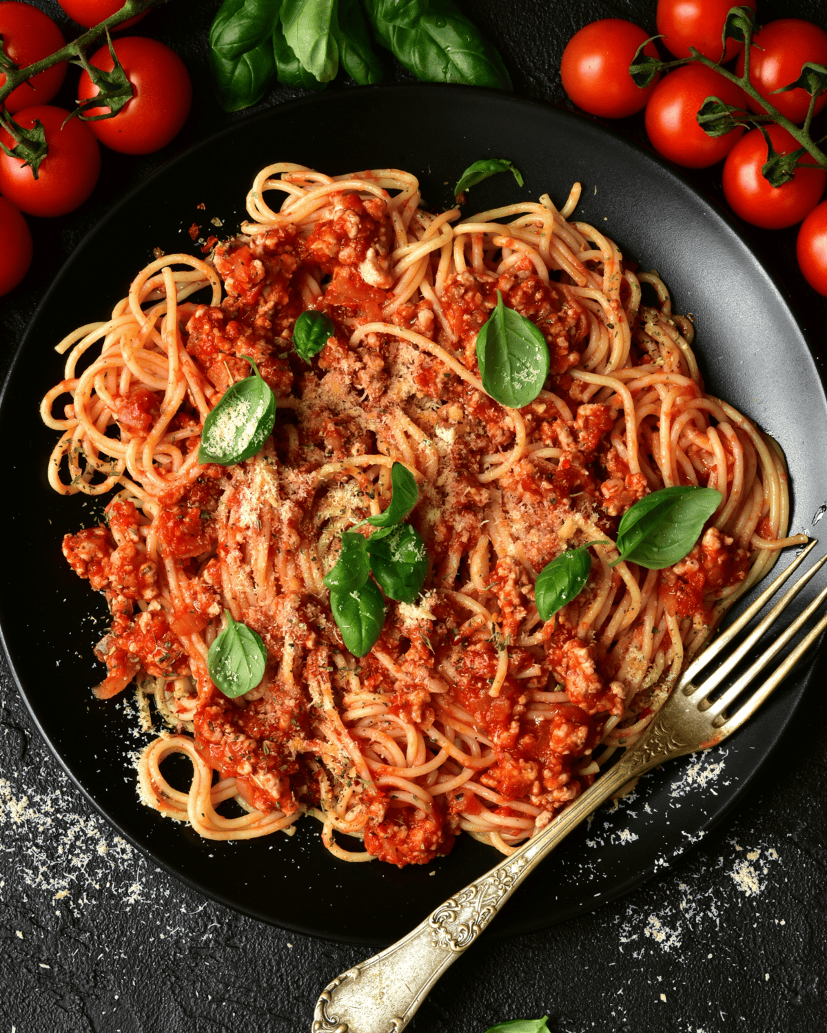 a plate full of spaghetti with meat sauce and basil leaves on top.