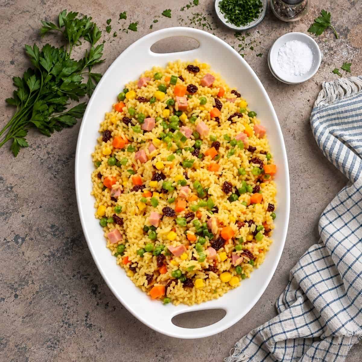 Overhead view of colorful Brazilian rice with ham, vegetables, and raisins.