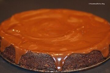 chocolate glaze being poured over chocolate nut cake