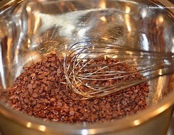 chocolate chips in a bowl being melted and stirred with a whisk