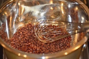 chocolate chips in a bowl being melted and stirred with a whisk