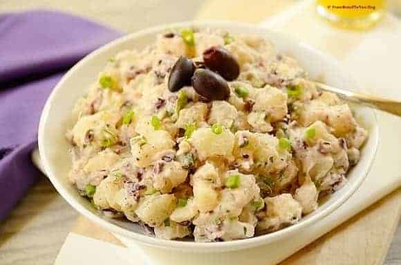 Brazilian potato salad with black olives on top and juice on the side