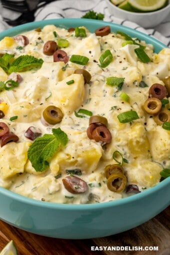 close up of a bowl of Brazilian potato salad with mayonnaise and garnishes on top
