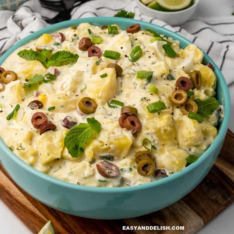 close up of a bowl of Brazilian potato salad with mayonnaise and garnishes on top