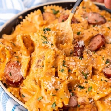 a plate with spicy sausage pasta with a spoon picking up part of the pasta