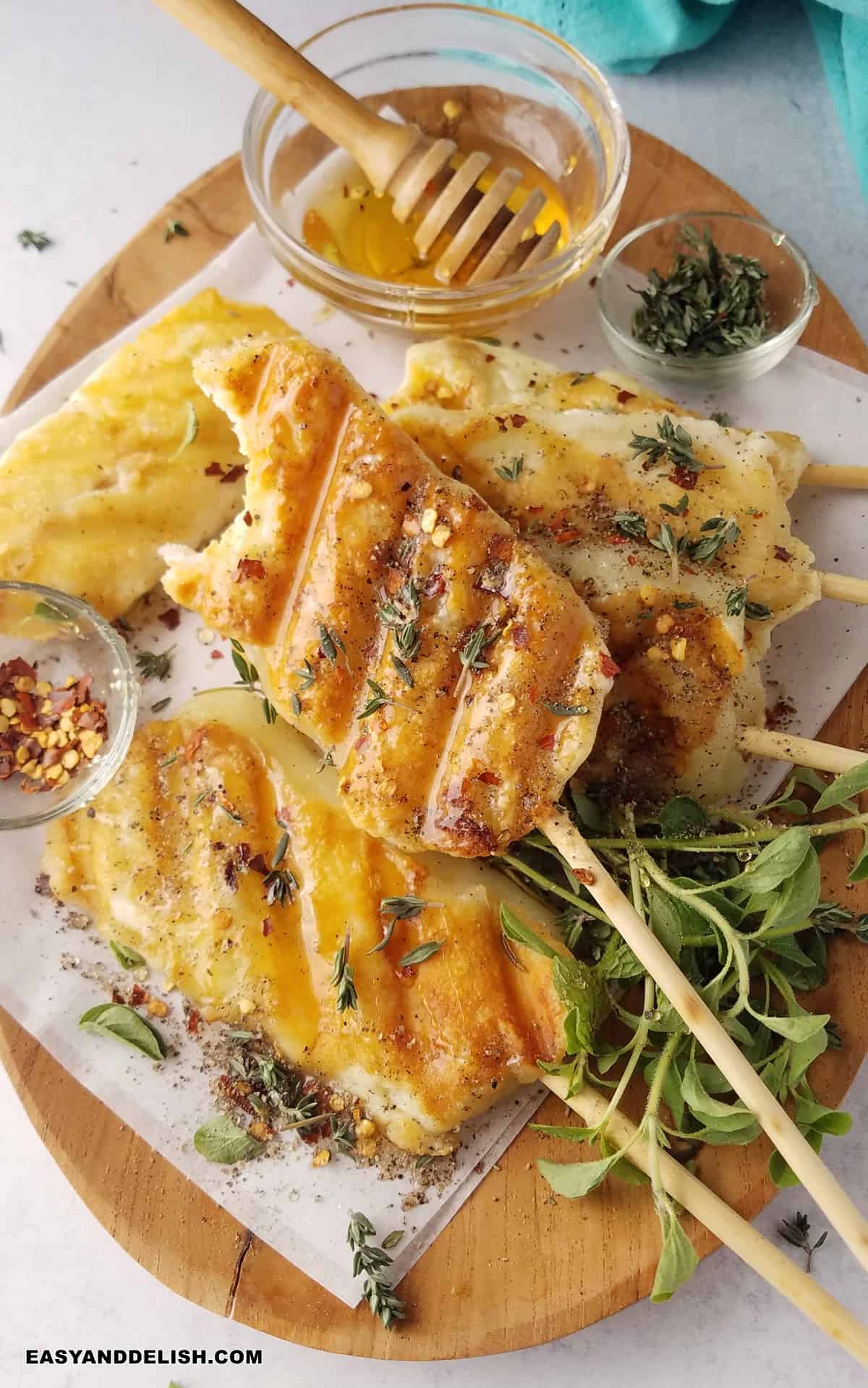 a tray full of grilled cheese on a stick and a side of herbs and honey.