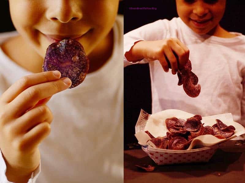 A person eating purple potato chips