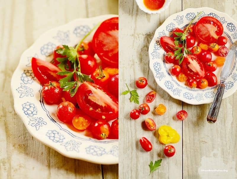 Red, orange, and yellow tomatoes on a wooden board and on a plate.