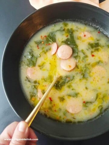 Caldo verde em uma tigela com uma mão segurando uma colher.