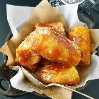 banana empanada com calda de caramelo por cima e açúcar de confeiteiro