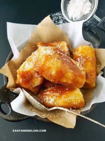 banana empanada com calda de caramelo por cima e açúcar de confeiteiro