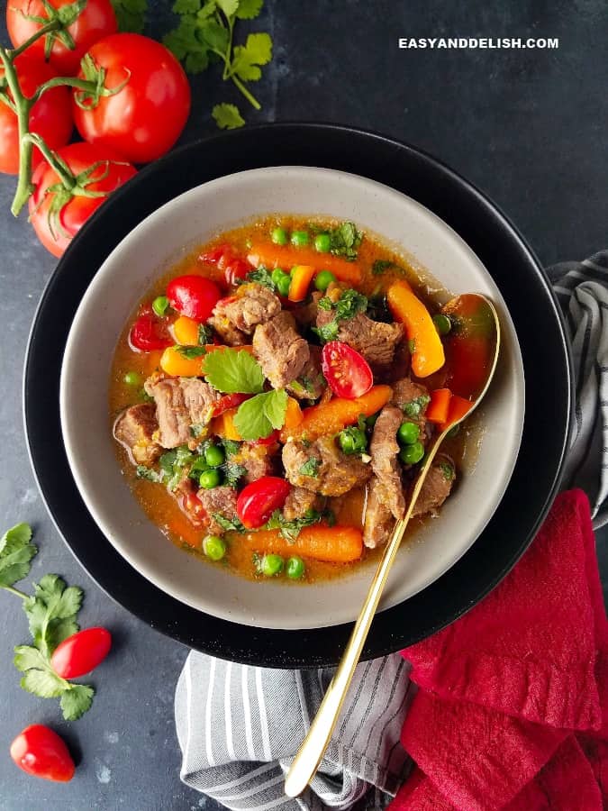 um prato com picadinhod e carne ao molho e legumes ao lado