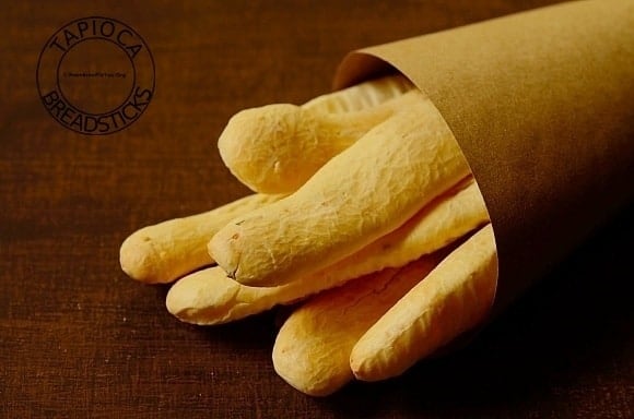 bunch of tapioca breadsticks on a table, wrapped in brown paper