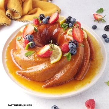 close up do pudim de pão inteiro e decorado com calda de caramelo e frutas