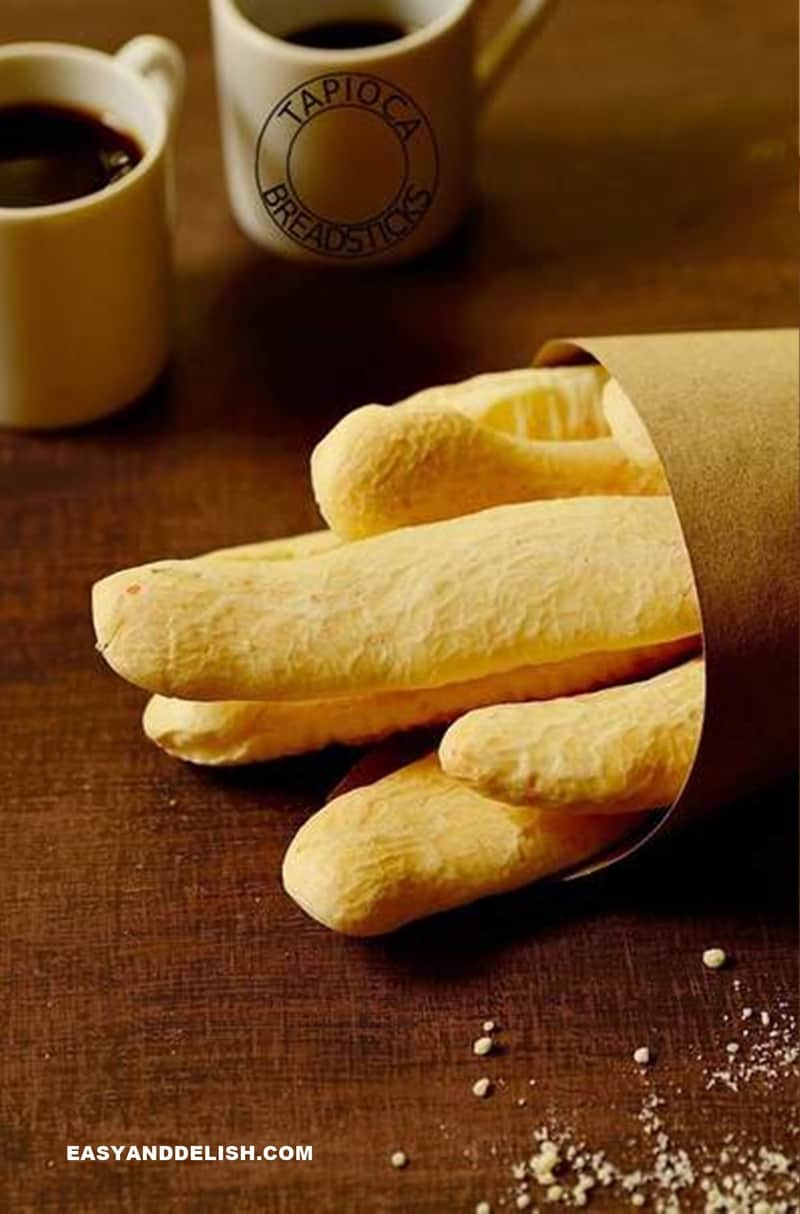 gluten-free breadsticks in a paper bag with 2 small cups of coffee on the background