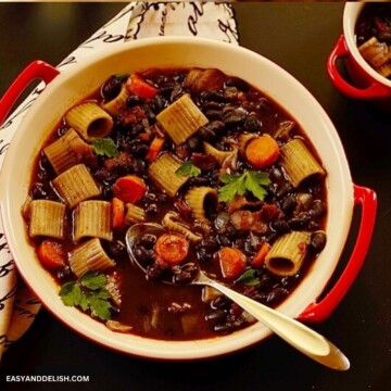 Black bean soup with bacon, vegetables, and pasta in a bowl.