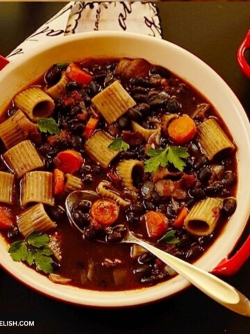 Black bean soup with bacon, vegetables, and pasta in a bowl.