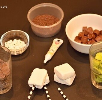 marshmallows, candy melts, straws, rolo chocolates, and chocolate sprinkles in dishes