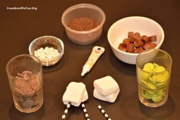 marshmallows, candy melts, straws, rolo chocolates, and chocolate sprinkles in dishes