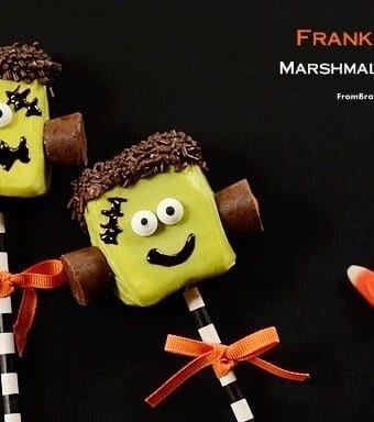 Two marshmallow candy pops decorated to like like Frankenstein's monster and tied with orange ribbons