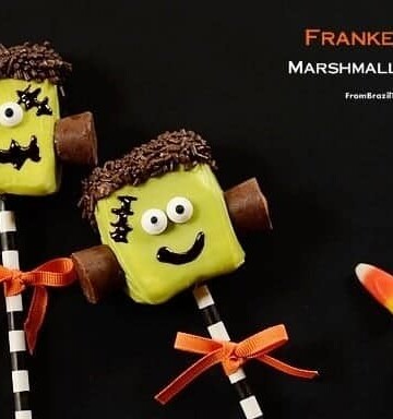 Two marshmallow candy pops decorated to like like Frankenstein's monster and tied with orange ribbons