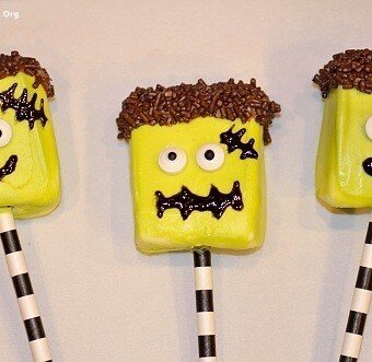 Three green frankenstein shaped marshmallow pops with candy eyes glued on