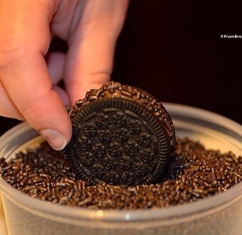 brigadeiro cookies being dredged in a container of chocolate sprinkles