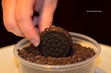 brigadeiro cookies being dredged in a container of chocolate sprinkles