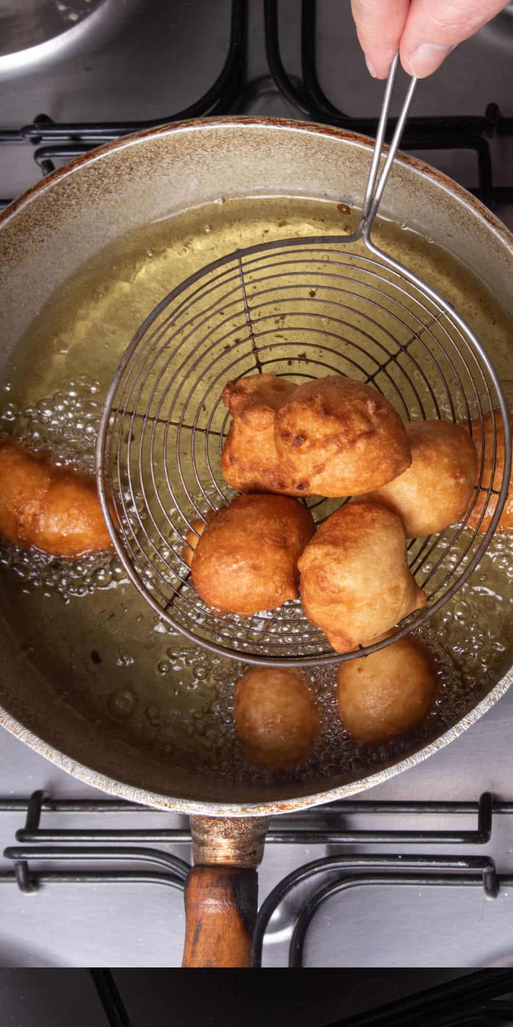 Removing donut holes from hot oil.