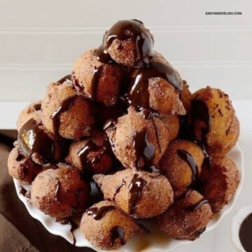 A tray with a pile of doughnut holes topped with chocolate ganache.