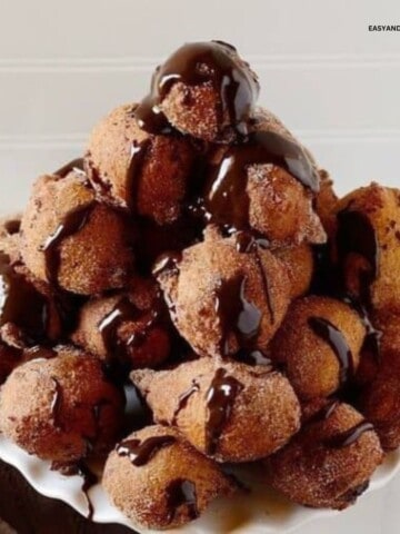 A tray with a pile of doughnut holes topped with chocolate ganache.