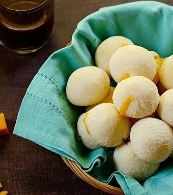 A basket of cheese rolls lined with a sea green cloth