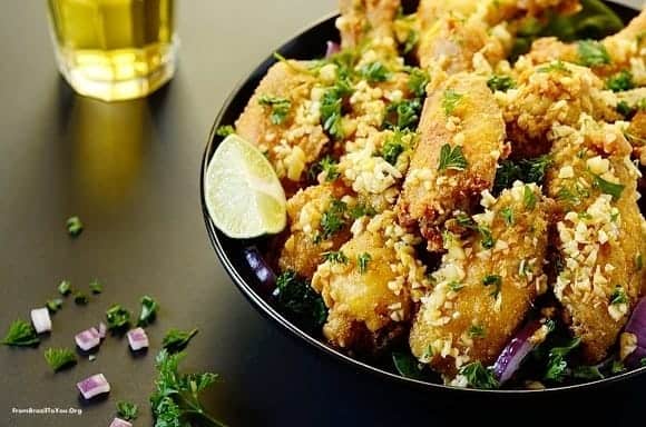 A plate of fried chicken wings with lemon garnish