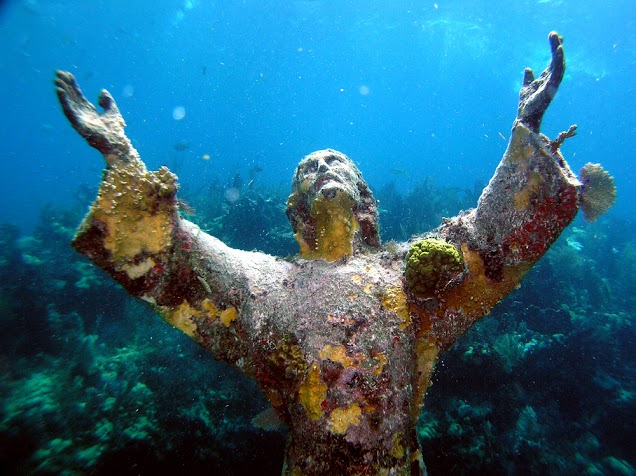 An underwater statue of Jesus looking to the sky