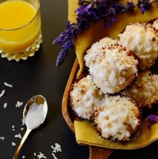 A pile of muffins on a board with a glass of orange juice