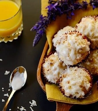 A pile of muffins on a board with a glass of orange juice