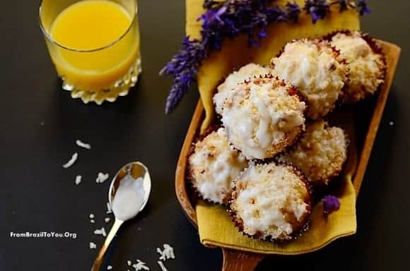 A pile of muffins on a board with a glass of orange juice