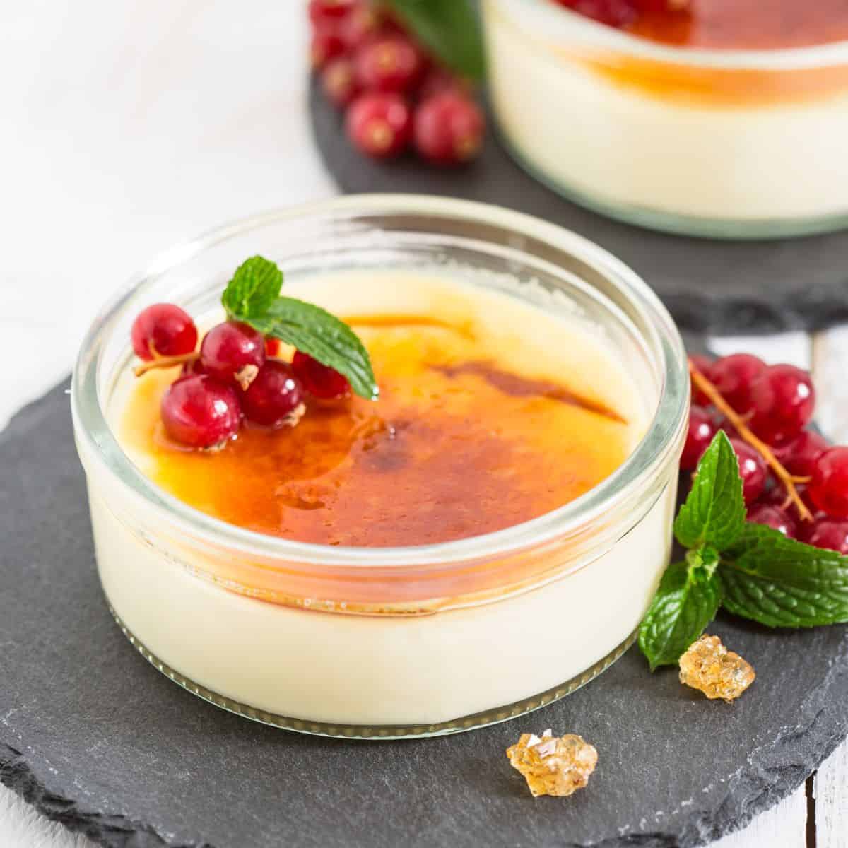 Ramekins with coconut creme brulee garnished with fresh currants and mint leaves.