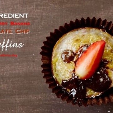 A baked banana muffin topped with chocolate chips and a strawberry
