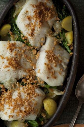 A bowl of cod fish with onions, garlic, and potatoes