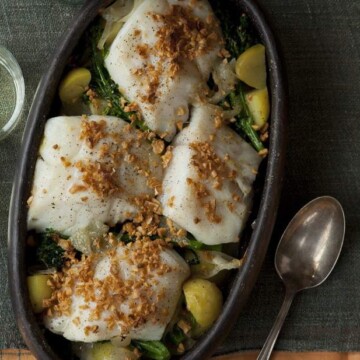 A bowl of cod fish with onions, garlic, and potatoes