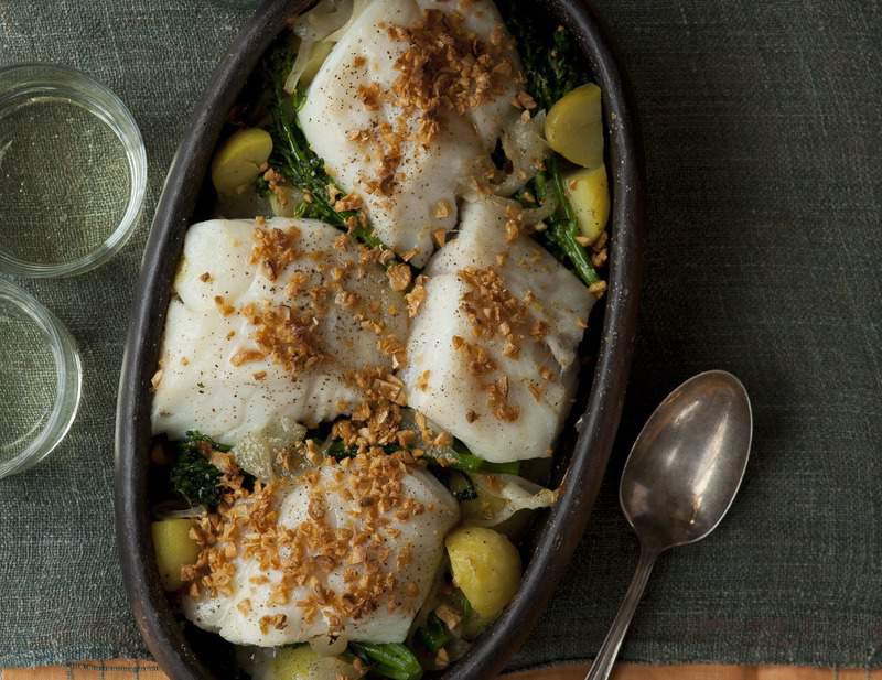 A bowl of cod fish with onions, garlic, and potatoes