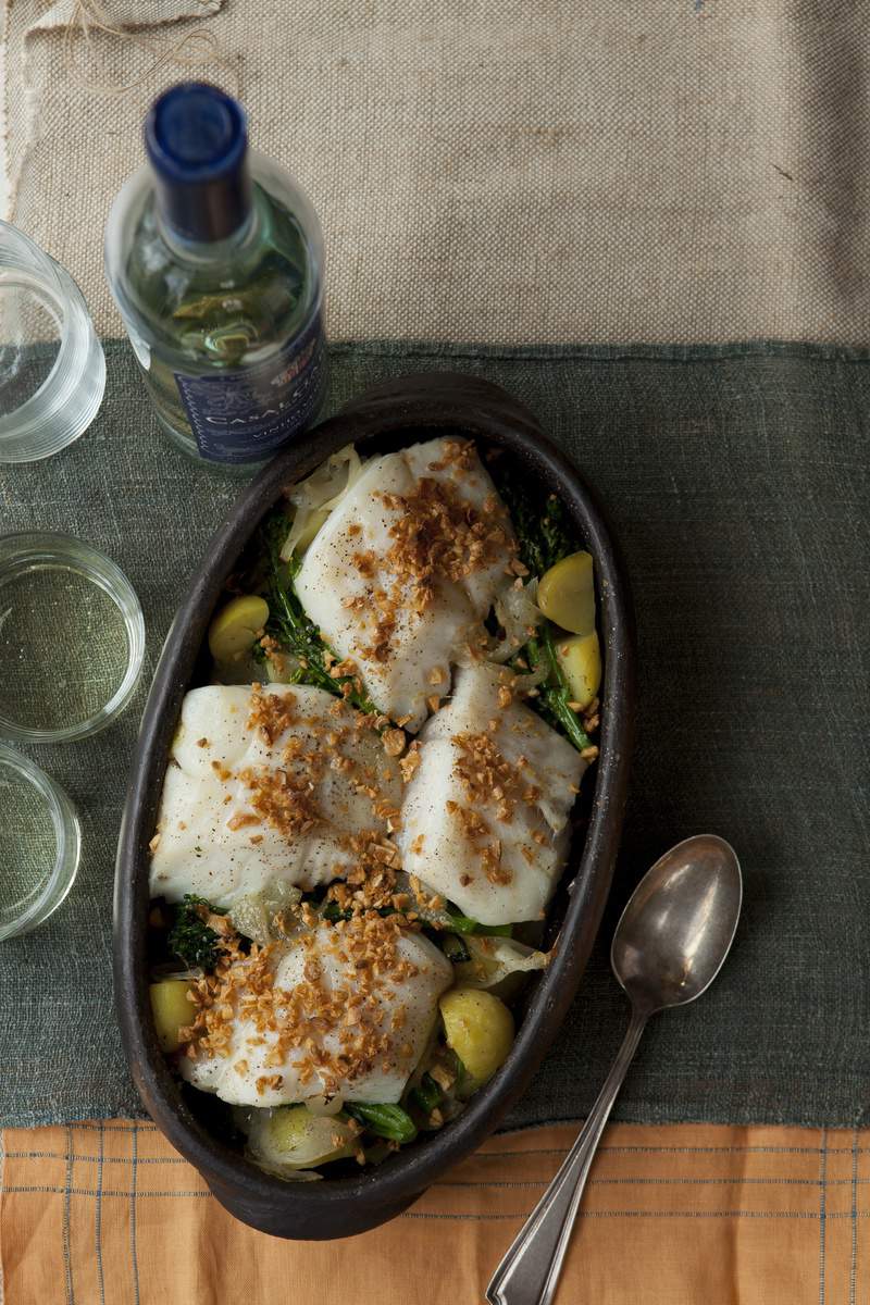 A stoneware dish of codfish, potatoes, and onions on a table