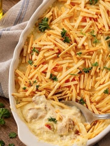 Creamy shredded chicken casserole topped with crispy shoestring potatoes and fresh parsley.